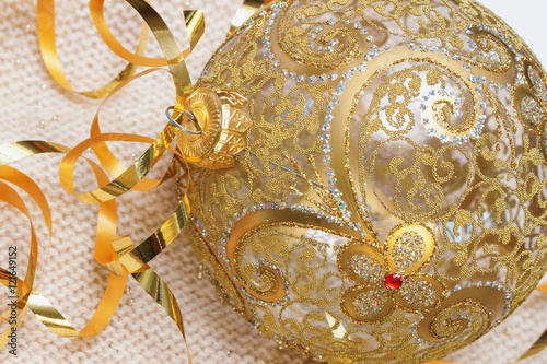 Golden Christmas ball with ribbons decoration glass  on a light knitted scarf,  and New Year's concept. Place for your text