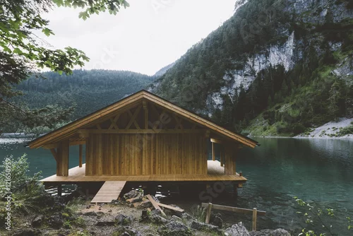 Obraz Drewniany dom na jeziorze z górami i drzewami
