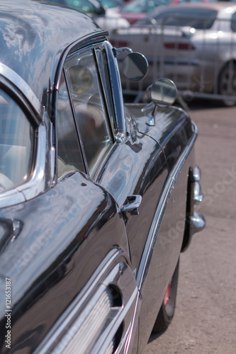 Close-up of an old car. Part of the exterior. An American classic. Chrome lining. Glass with reflection.