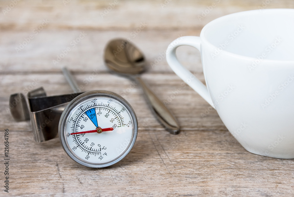 The thermometer for coffee, coffee cups and a spoon placed on a wooden floor. The thermometer for coffee, coffee cups and a spoon placed on a wooden floor.