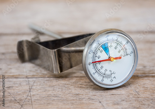 The thermometer for coffee or tea placed on the wooden background.