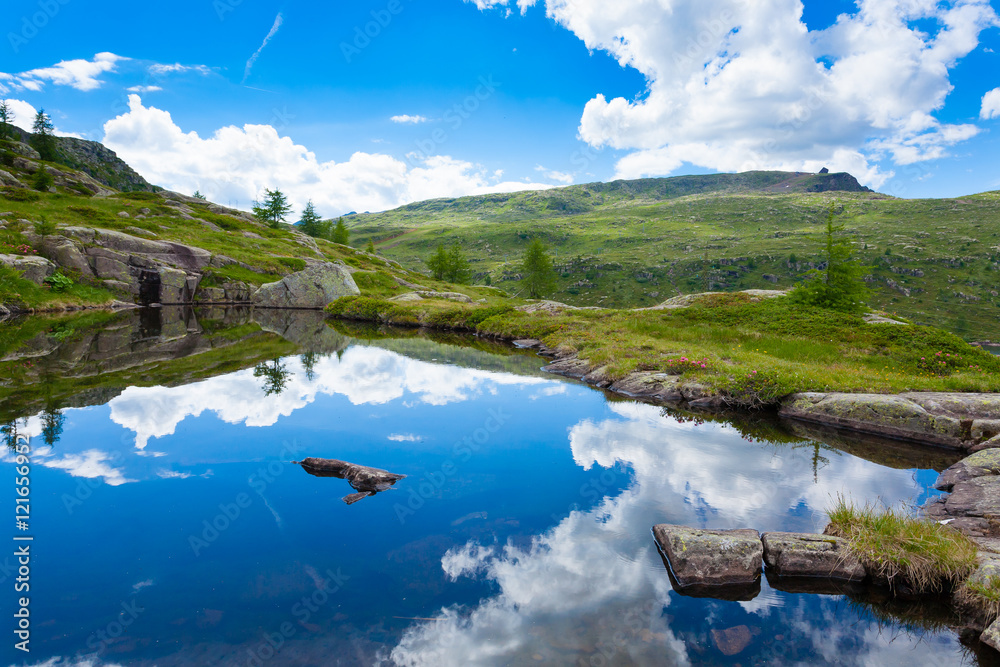 Italian mountain panorama, clouds reflected on alpine lake