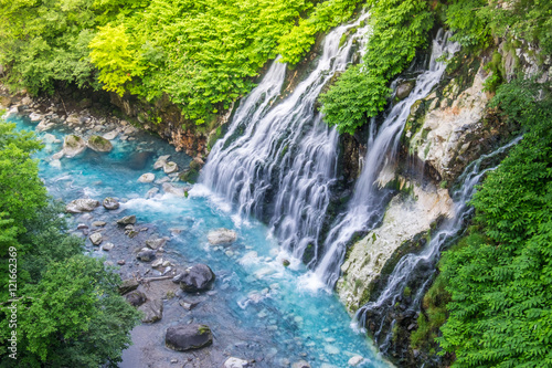Fototapeta Naklejka Na Ścianę i Meble -  Shirogane waterfall with blue stream at Biei, Japan