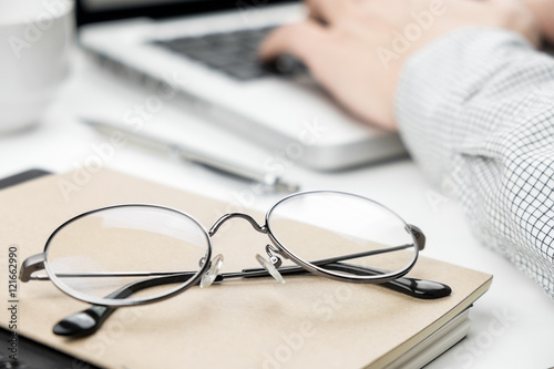 Close-up of eye glasses with a business man working on laptop in
