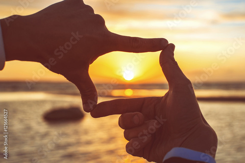 Composition finger frame- man's hands capture the sunset photo