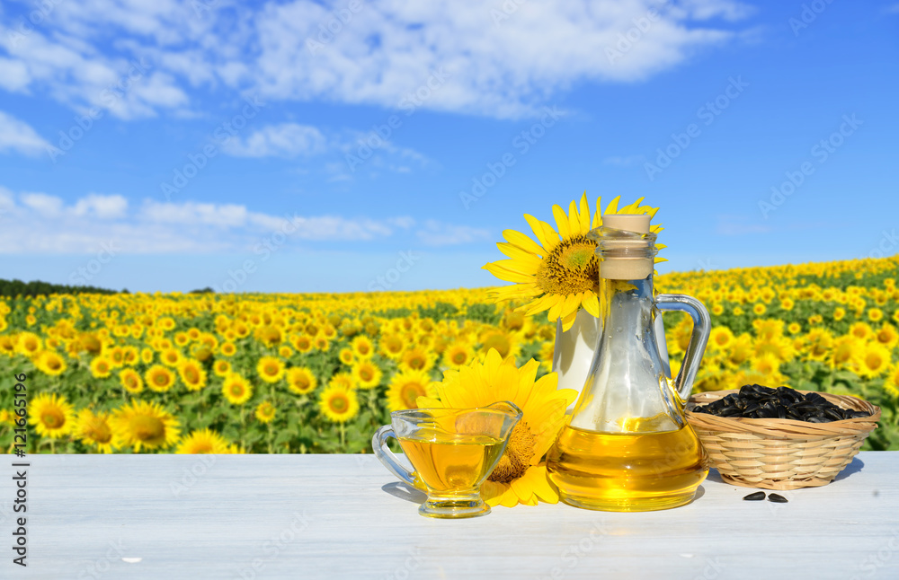 Fototapeta premium Sunflowers, seeds and sunflower oil. In the background a field of sunflowers