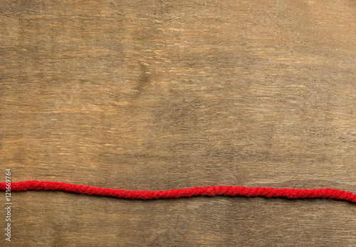 The red thread above vintage wooden background in the lower part