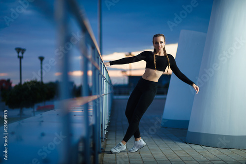 Concept: healthy lifestyle, sport. Attractive happy girl fitness trainer do outdoor workout at modern downtown urban area during sunset.