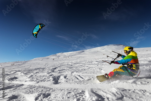 Snowboarder skydives on blue sky backdrop in snow mountains
