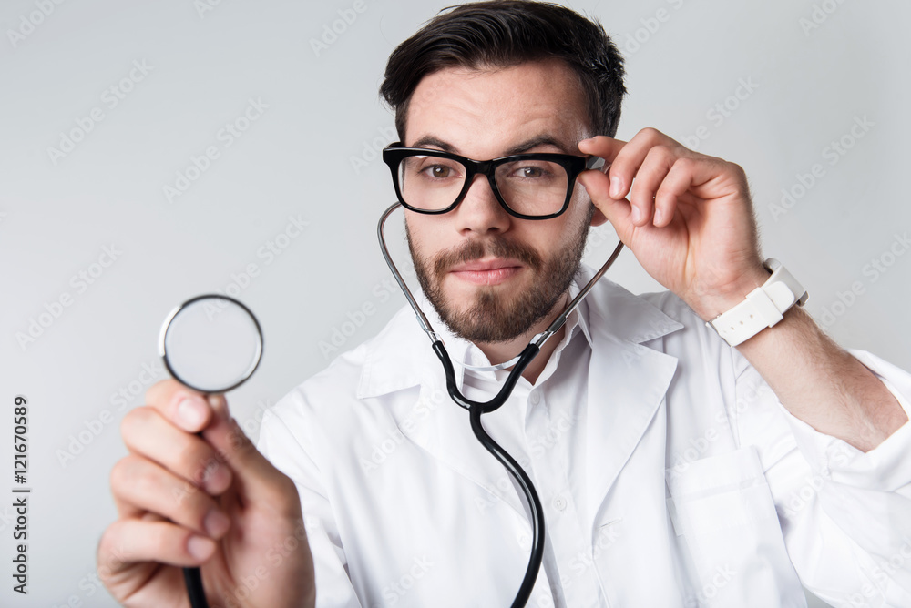 Concentrated bearded man holding stethoscope. Concentrated bearded man holding stethoscope.