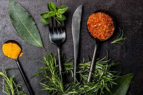 Food black background with herbs, spices and cutlery. top view photo