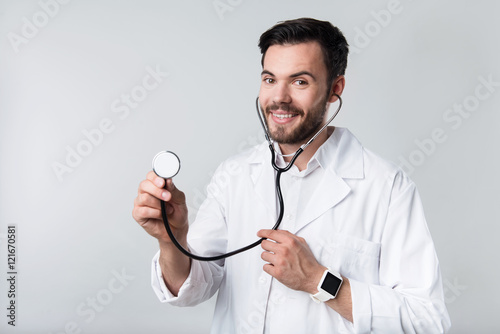 Smiling good looking man demonstrating stethoscope.