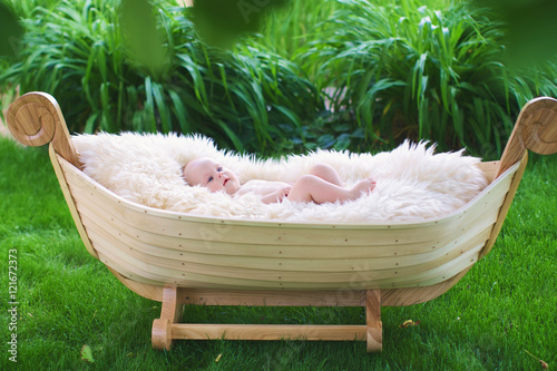 Infant lies in wooden cradle photo