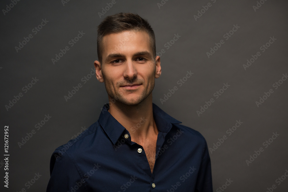 Man in black shirt looking t camera and smiling isolated on grey background. Fashion or vogue concept. Picture of handsome model man posing in studio for photographer. Man in black shirt looking t camera and smiling isolated on grey background. Fashion or vogue concept. Picture of handsome model man posing in studio for photographer.