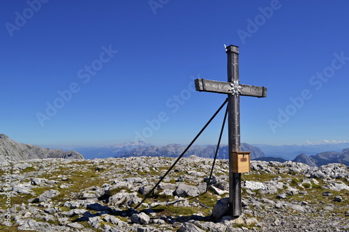 Wooden cross on a mountain top with stones and grass Berchtesgaden's Alps