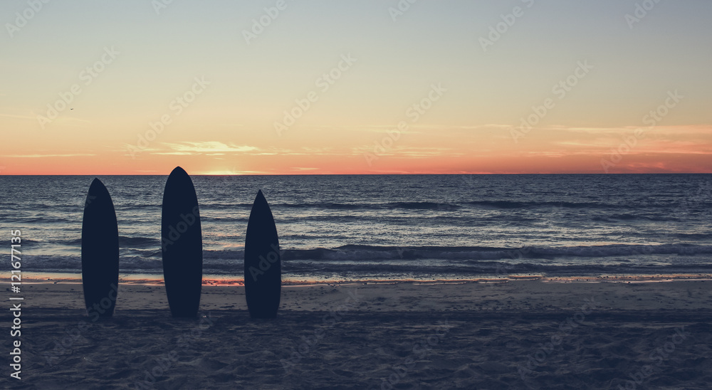 Retro  photo of a  silhouette of surfboards on the  beach at sunset 