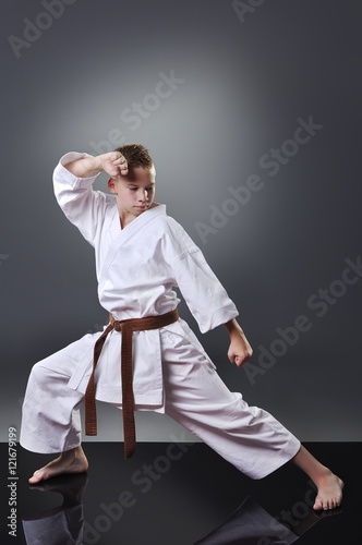 Handsome young male karate doing kata on the gray background