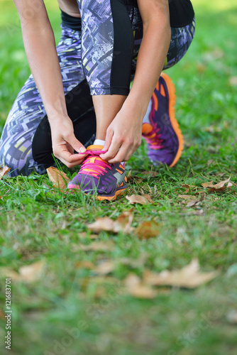 Female jogger tying laces on her shoes outside