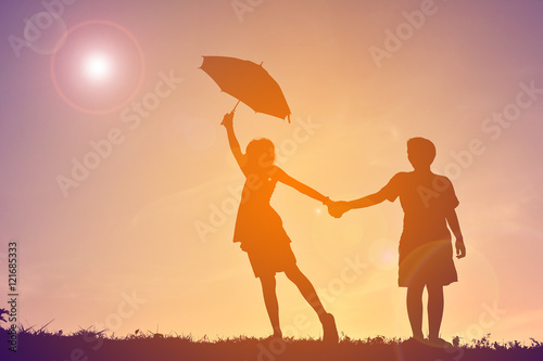 Silhouette children with umbrella on sunset