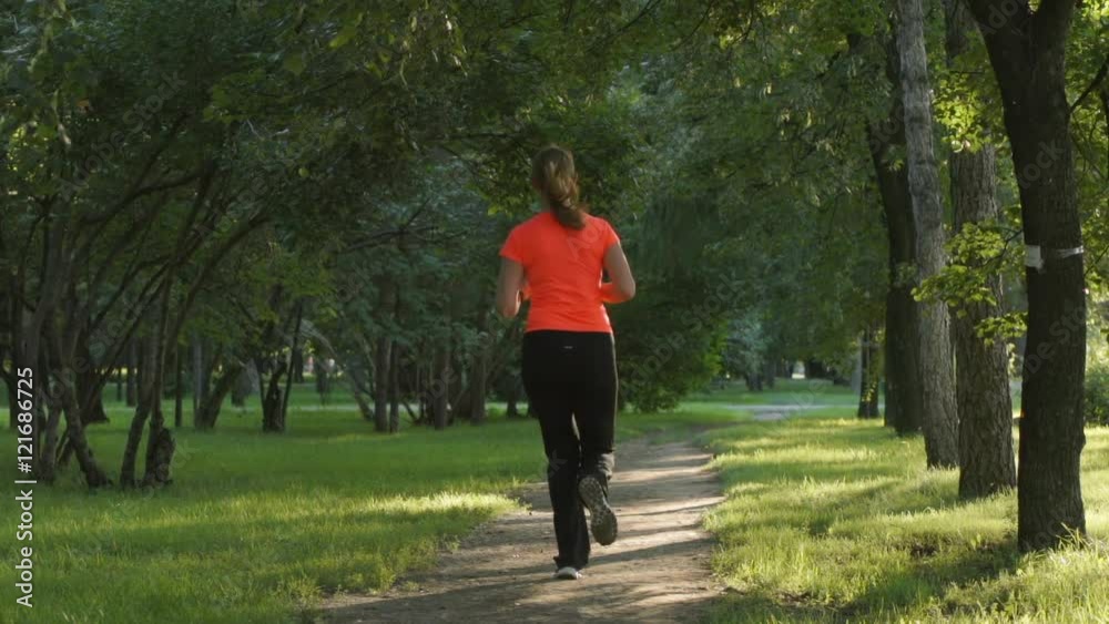 SLOW MOTION: Young woman runs on a path SLOW MOTION: Young woman runs on a path
