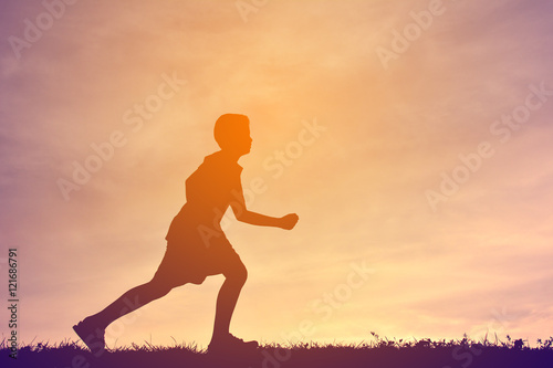 Fototapeta Naklejka Na Ścianę i Meble -  Silhouette a boy running on sunset