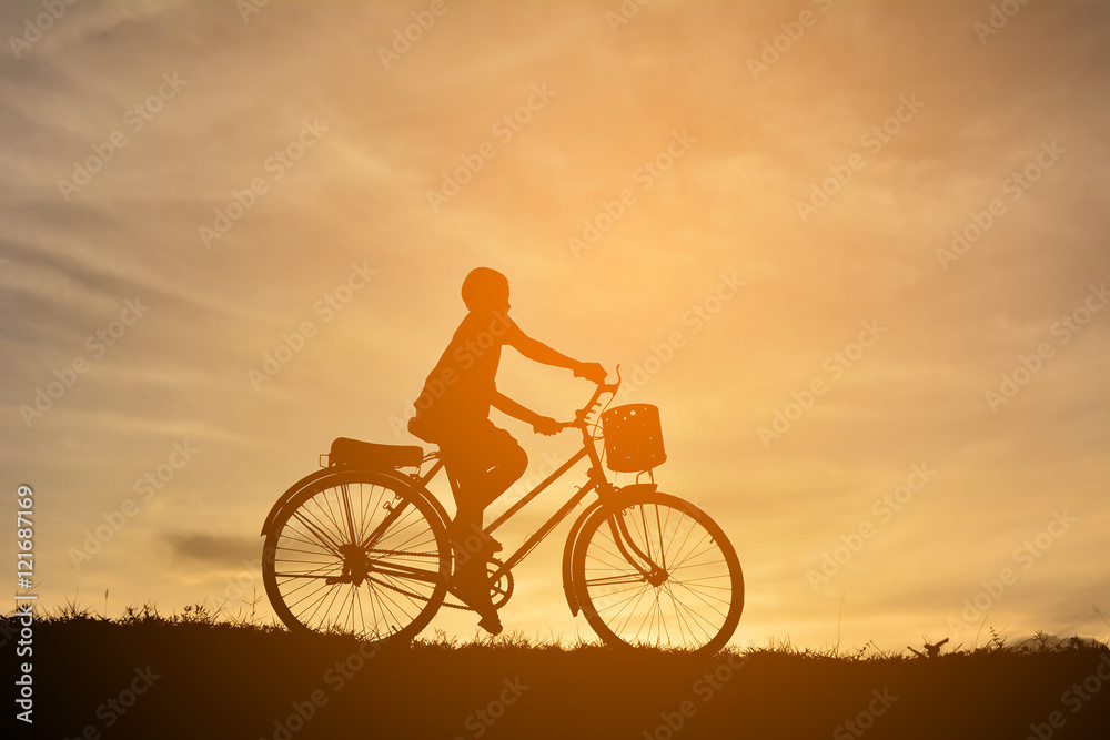Silhouette a boy with bicycle at sunset