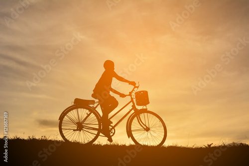 Silhouette a boy with bicycle at sunset