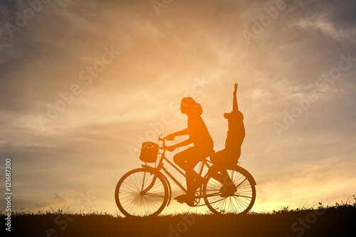 Silhouette women and boy with bicycle on sunset