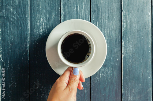 hands holding mug of hot drink on wooden table