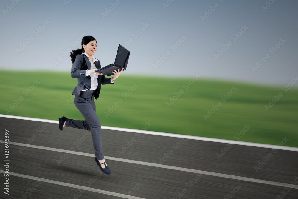 Female worker with laptop running on track
