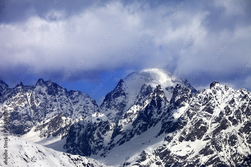 Fototapeta premium Snow mountaims in clouds at sunny winter day