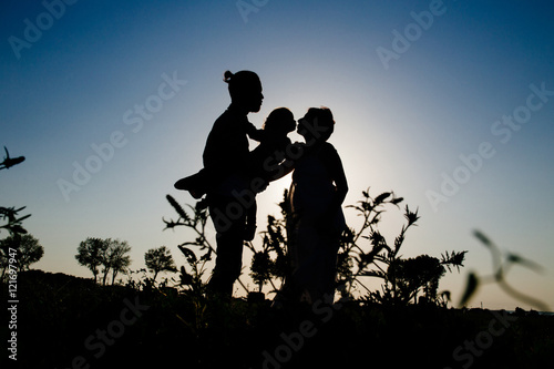 silhouette of a happy family with a child in a field