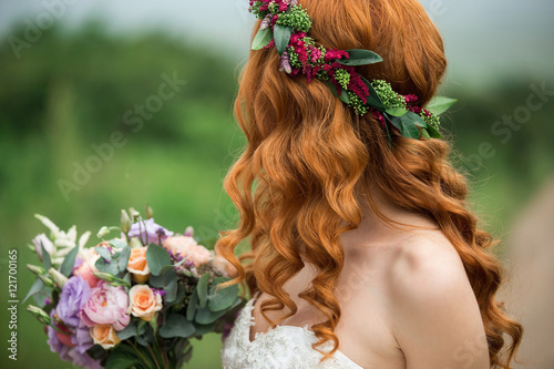 Bride in the park. Red-haired woman. The hair of the girl wreath of flowers.