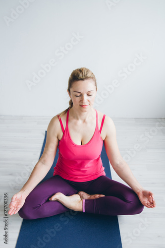Young woman in a white room doing yoga exercises .