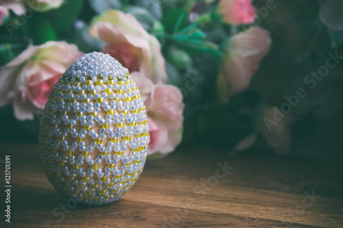 Easter egg from beads next to pink roses photo