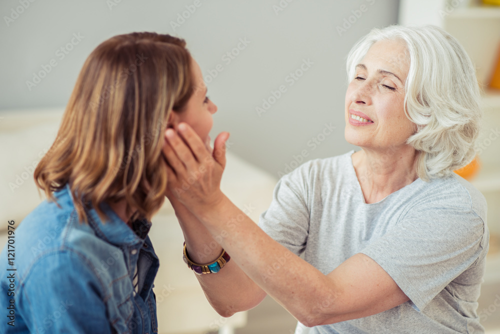 Delighted loving senior woman holding cheeks of her daughter Delighted loving senior woman holding cheeks of her daughter