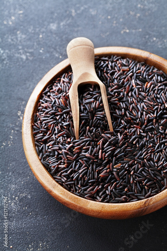 Closeup of black rice in wooden bowl on a dark table