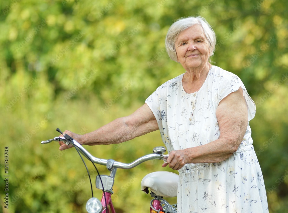 Senior woman with bike in park.