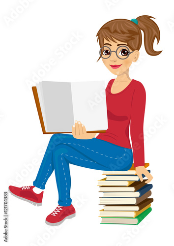 young female student with glasses sitting on stack of books showing open textbook