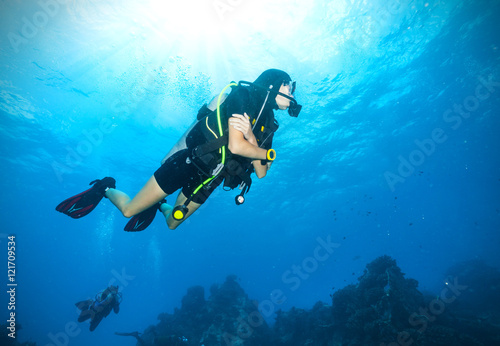 Young woman scuba diver exploring sea bottom