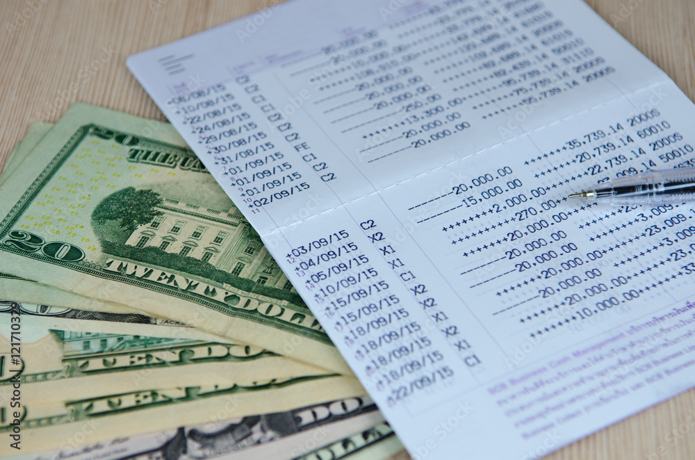 Pen on bank account passbook with dollar banknote, selective foc Pen on bank account passbook with dollar banknote, selective foc