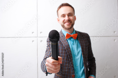 The interviewer. Young bearded man in plaid suit with microphone. Focus on microphone.