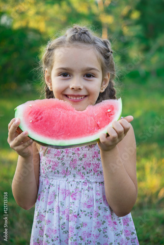 little girl with slice of watermelon in the garden