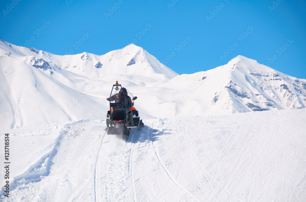 Extreme drive in mountains by snowmobile. Sport healthy weekend in snowy valley with fresh air. Man rush to the rescue to ski or snowboard crush.