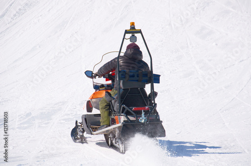 man drive snowmobile in mountains. ski resort staff. extreme driving with perfect winter landscape. Snow riding to the peak. photo