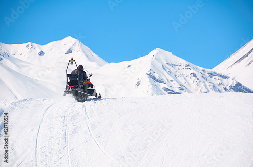 man drive snowmobile in mountains. ski resort staff. extreme driving with perfect winter landscape. Snow riding to the peak. Copy space for text