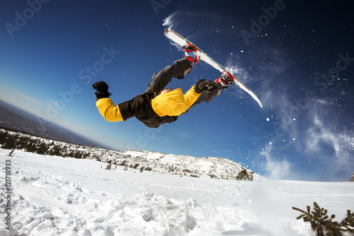 Snowboarder posing on blue sky backdrop in mountains