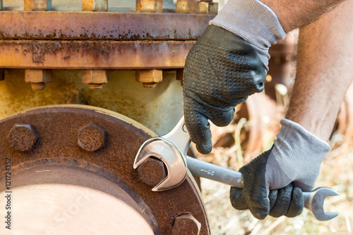 Hands with Work Gloves Holding a Wrench and Tighten very Rusty Bolts