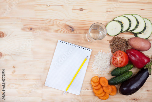 vegetables and cereals and notebook on a wooden table. Healthy E