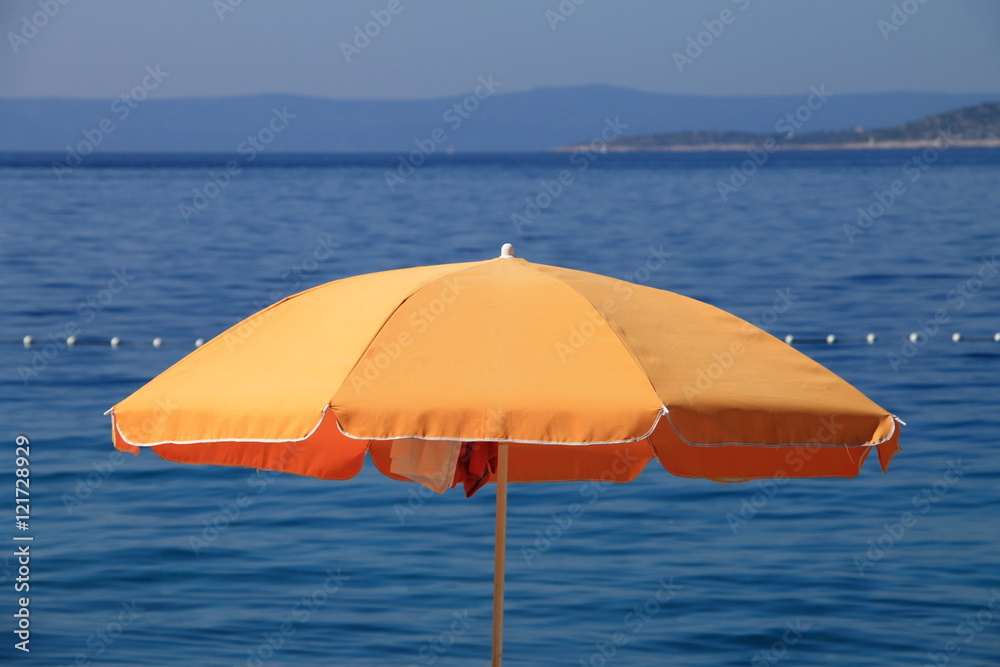 Orange beach umbrella near the Adriatic sea in Brela , Croatia